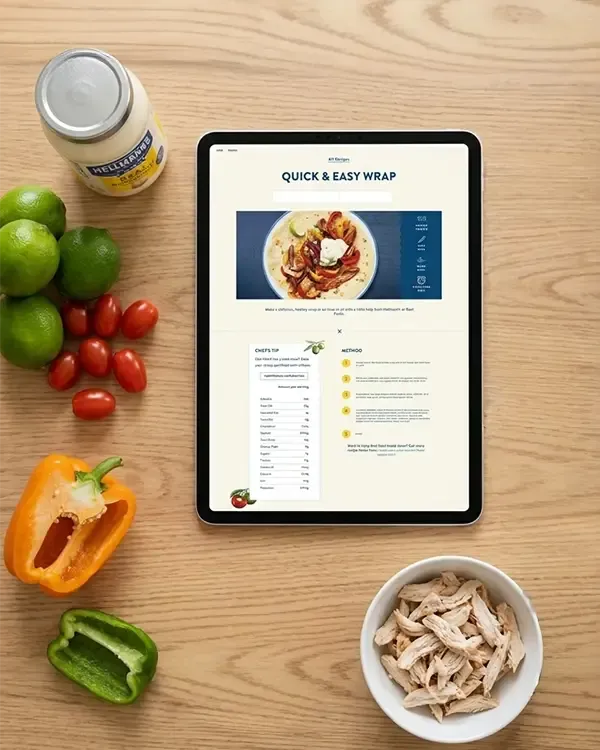 Hellmann's recipe page shown on a tablet beside fresh vegetables